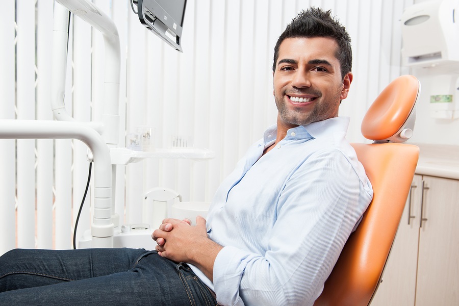 Hispanic man sitting in dental exam chair, Windsor Locks, CT crowns
